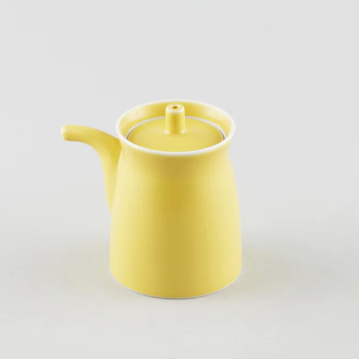 Yellow ceramic soy sauce pot on a light gray background